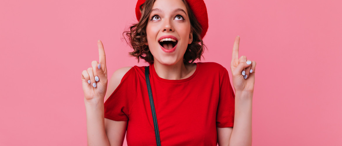 Ecstatic french girl with tattooes smiling on pink background. Surprised elegant woman in red beret looking up.
